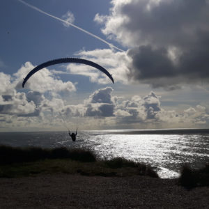 Steilküste Paraglider fliegt gerade im Gegenlicht los