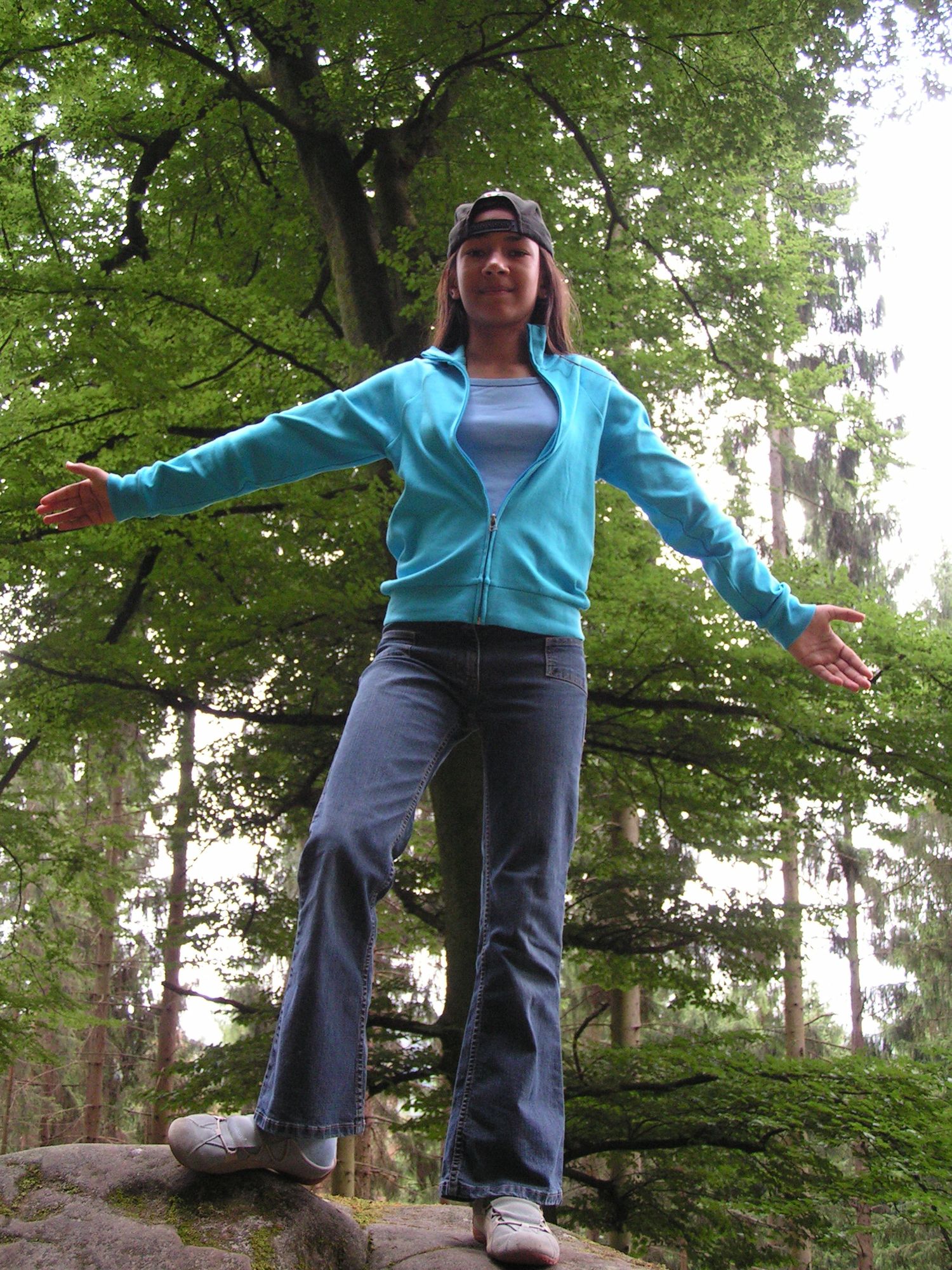 Sophia posiert auf einem Stein im Wald