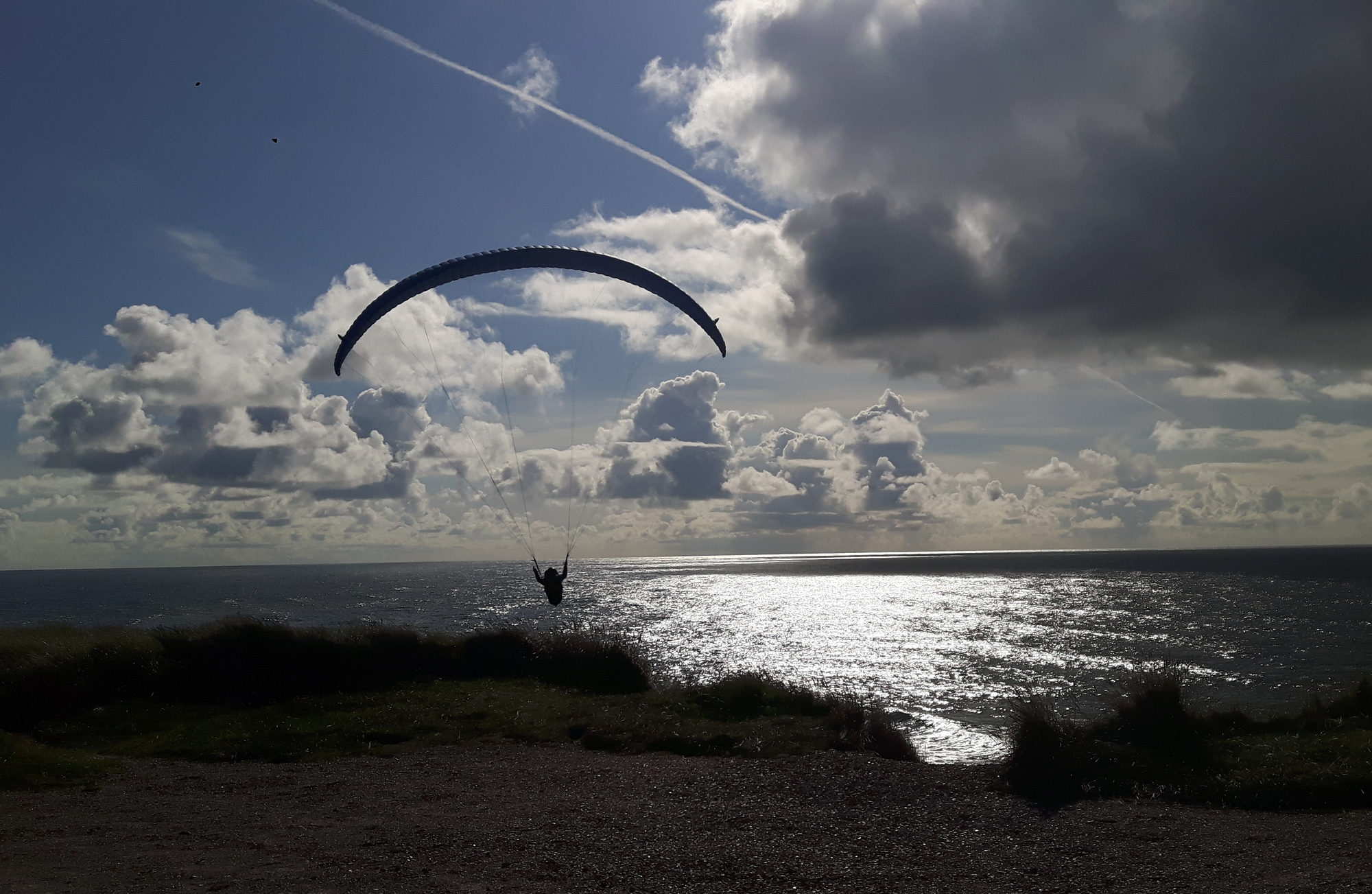 Steilküste Paraglider fliegt gerade im Gegenlicht los
