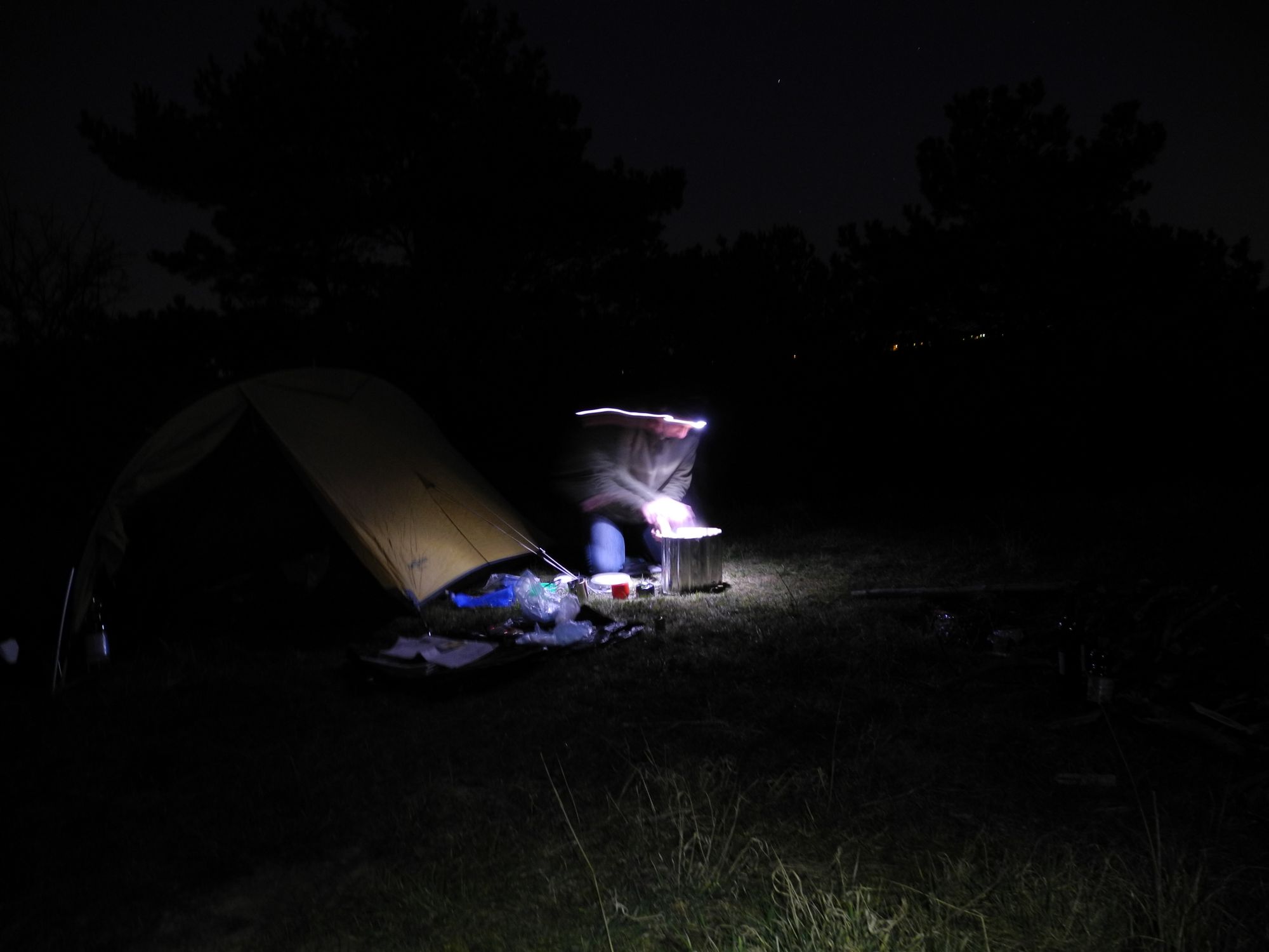 Kochen mit Stirnlampe vor dem Zelt im Dunklen
